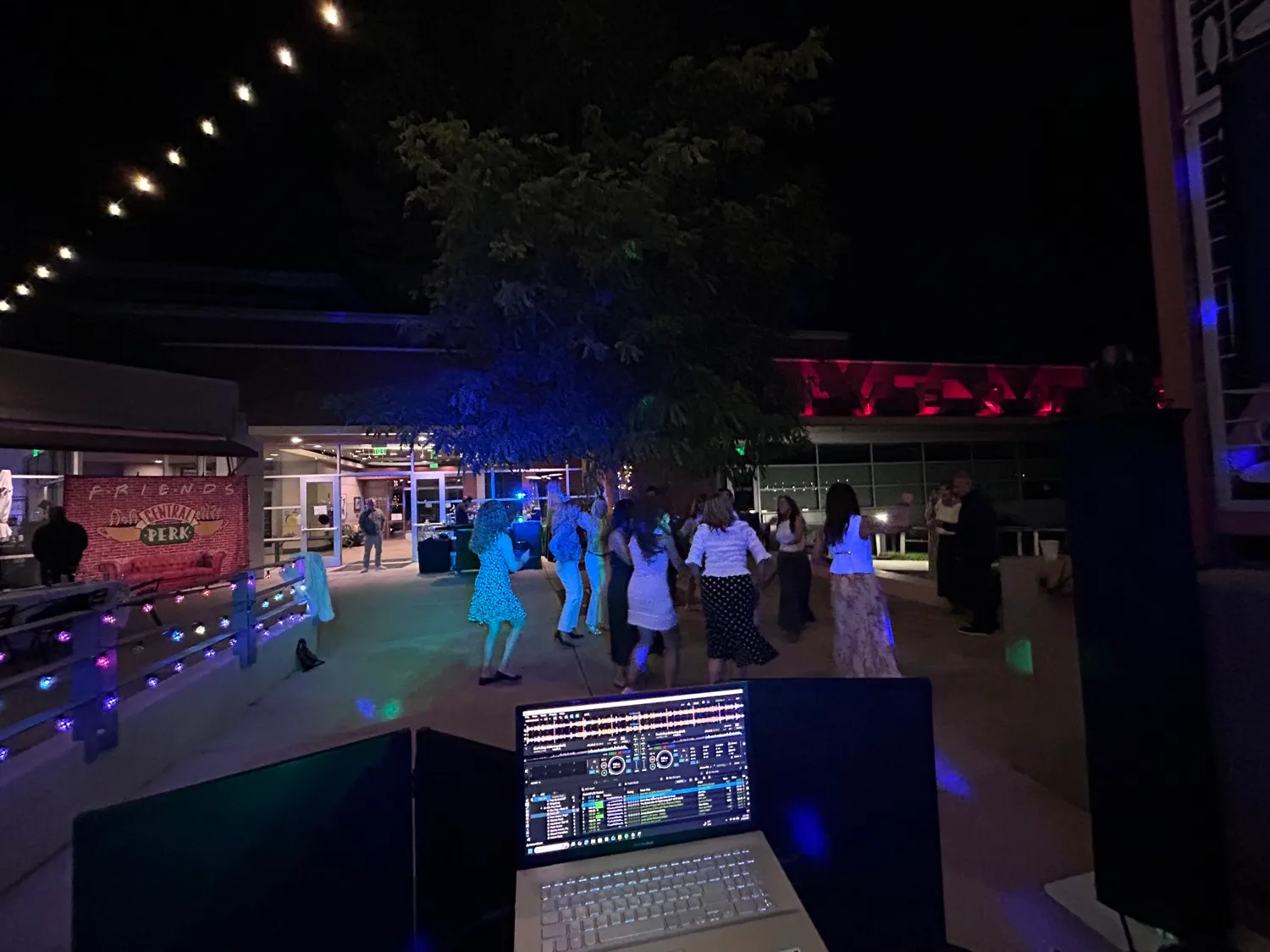 Guests dancing under string lights in the evening